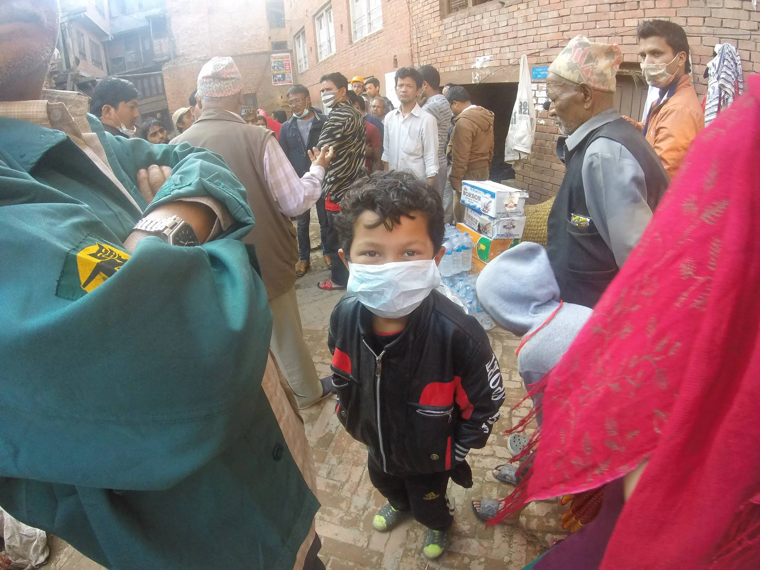 Young boy in Bhaktapur surrounded by family and neighbors all of whom lost their homes