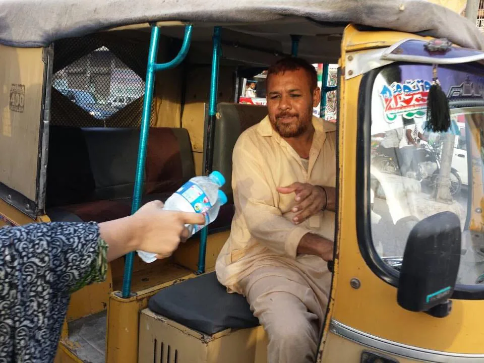 Volunteers of Elaj Trust hand out bottles of water at Karachi’s busy intersections in June