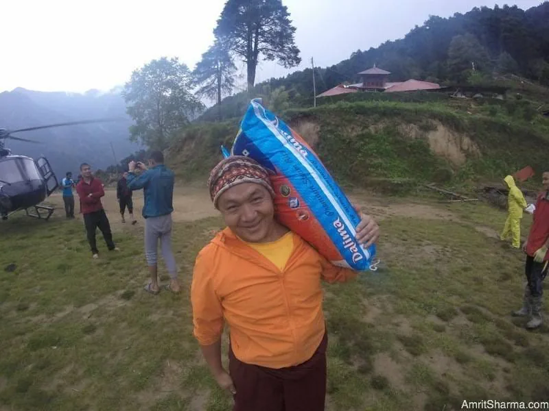 Man carrying a 30kg bag of rice for his village